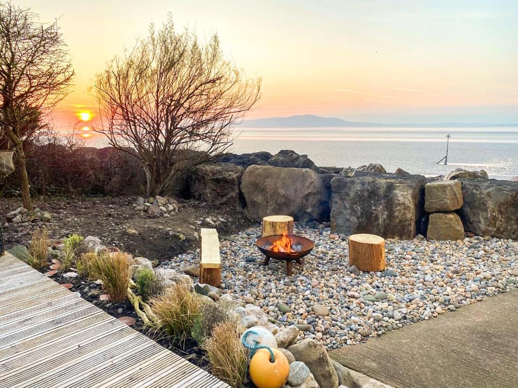 a fire pit in the middle of a beach with the sunset at Redgauntlet in Skinburness