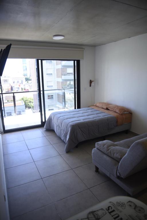 a bedroom with a bed and a couch and a window at Tigre-Estación Fluvial Monoambiente in Tigre