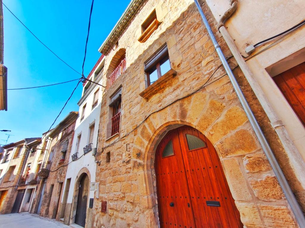 a brick building with a red door on a street at Amplia Casa en Vinaixa, calle Mayor, Cal Mitger in Viñaixa