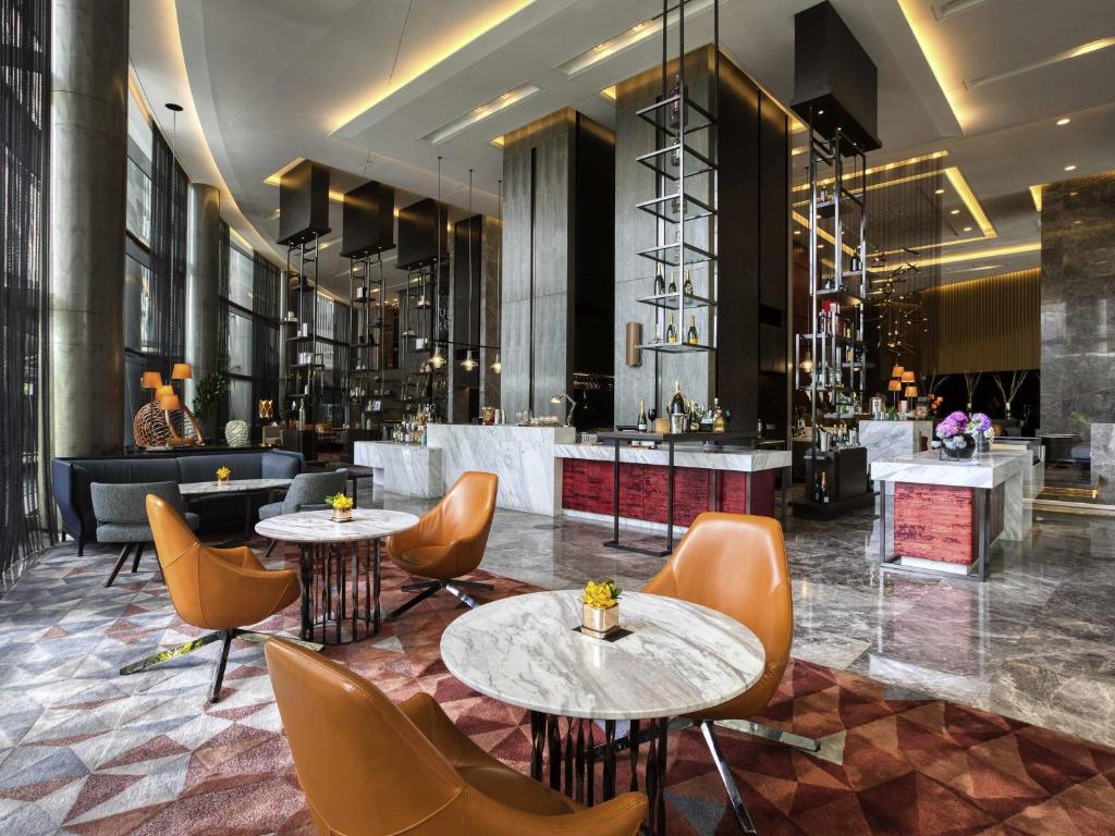 A high-ceilinged lobby lounge with marble tables, leather chairs and a bar.