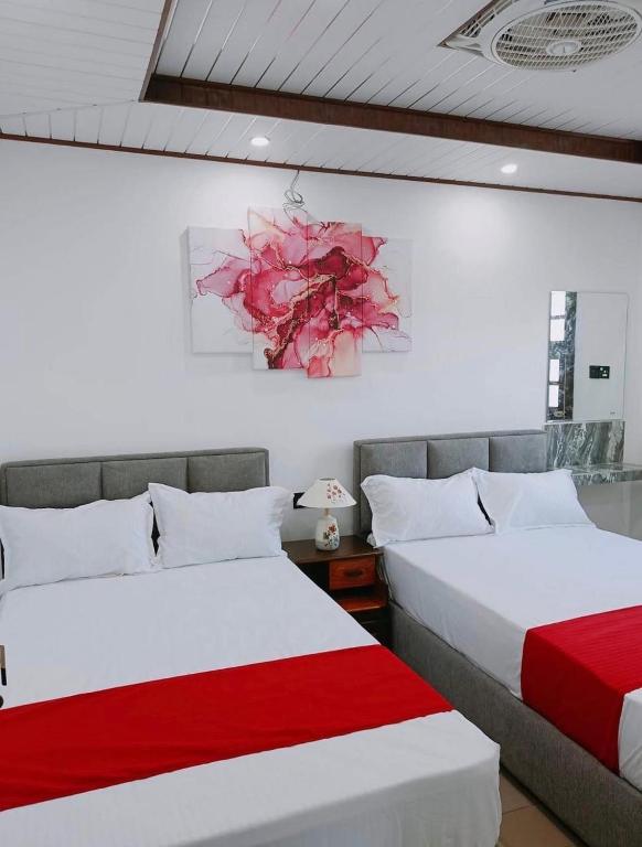 two beds in a room with red and white at Hotel Kandy road in Meda-Ela