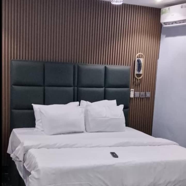 a bedroom with a large bed with a blue headboard at Transvent Hotel and Suites in Abeokuta