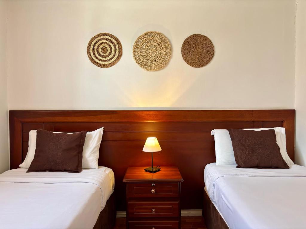 a bedroom with two beds and a table with a lamp at El Patio Hostel Quito in Quito