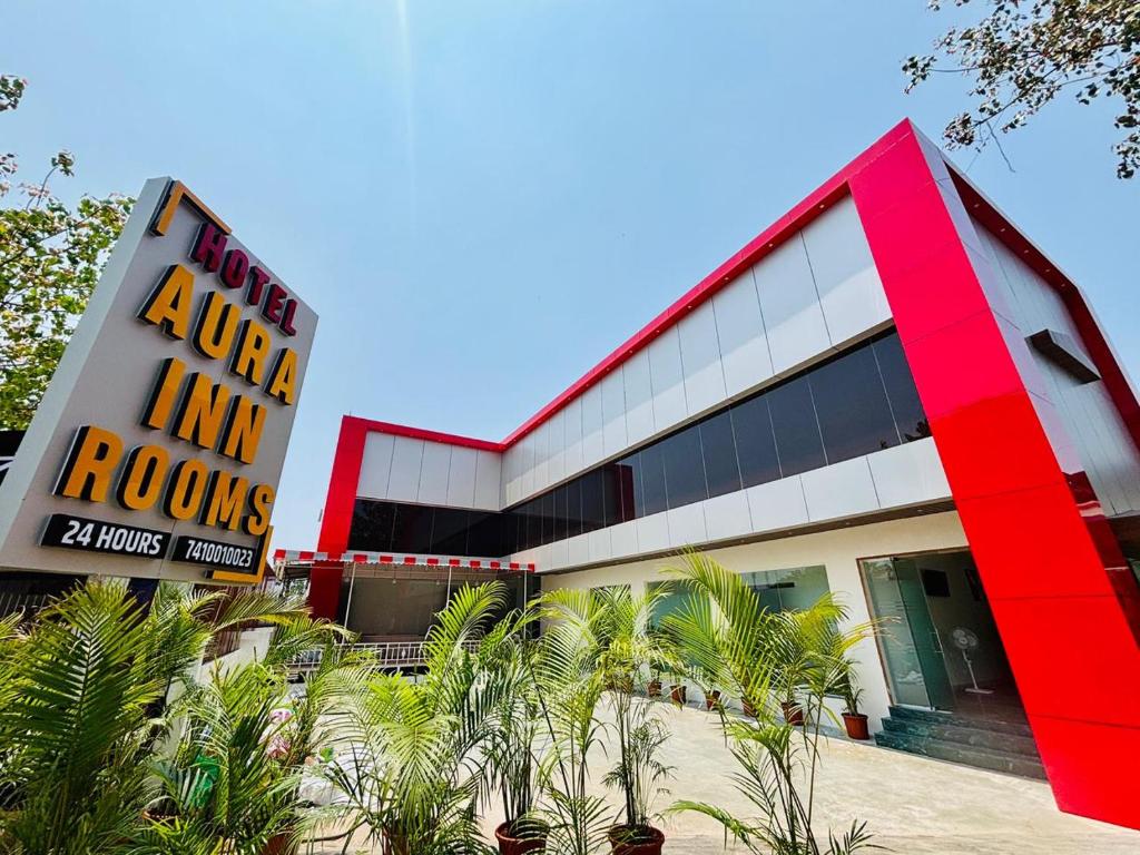 a red and white building with a sign at Hotel Aura Inn in Dehu