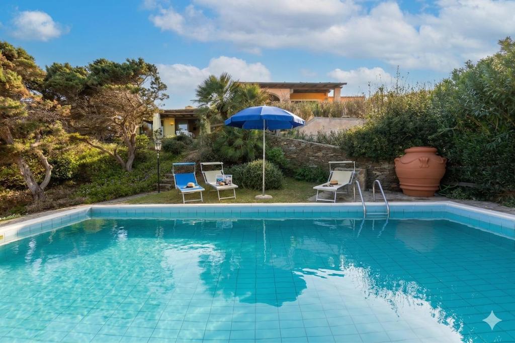 a swimming pool with two chairs and an umbrella at Villa Belvedere Saline - Private Pool in Stintino
