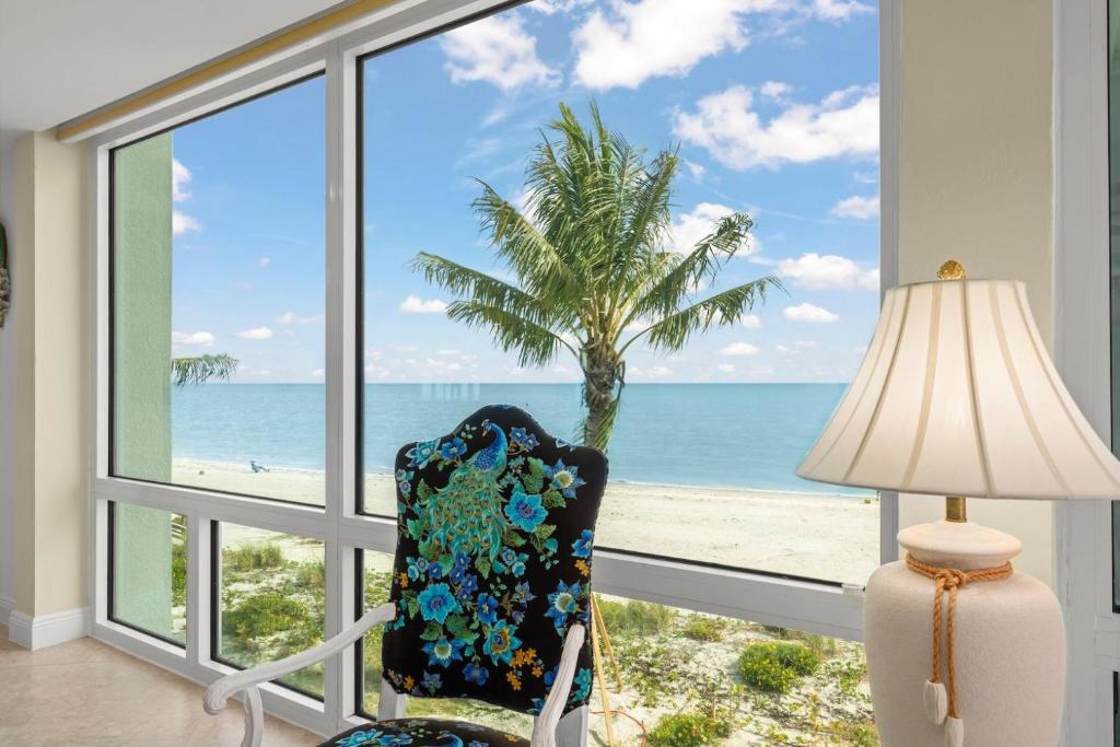 a room with a chair and a palm tree and the ocean at Island Beach Club #360D in Sanibel