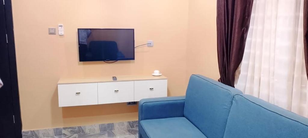 a living room with a blue chair and a tv at Transvent Hotel And Suites in Abeokuta