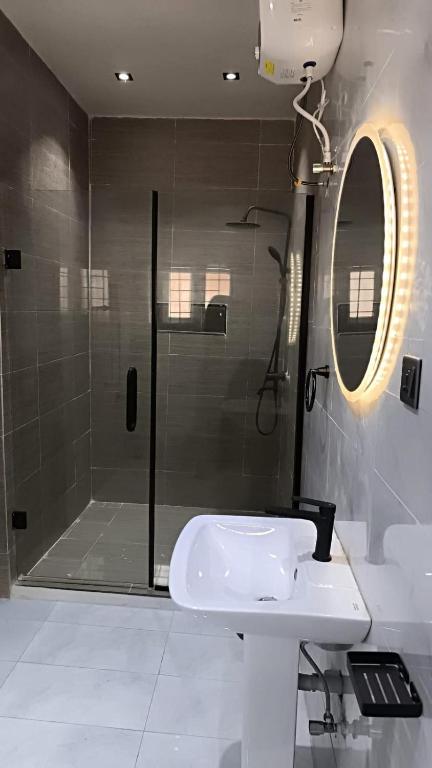 a bathroom with a shower and a sink and a mirror at Cosmo Haven Suites - Self Contained Apartment in Ibadan
