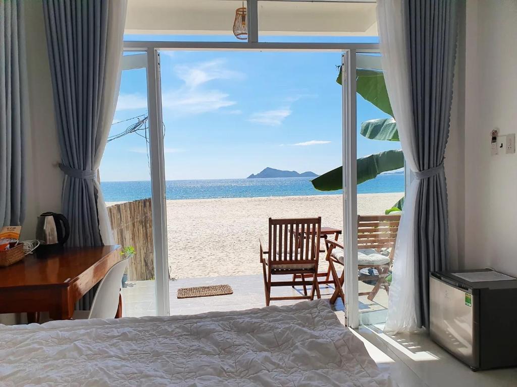 a bedroom with a bed and a view of the beach at Ocean Breeze Bungalow in Sông Cầu