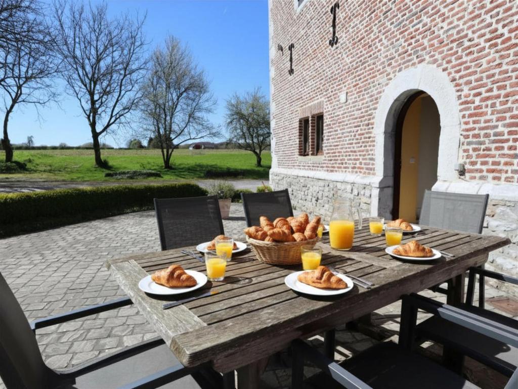 a wooden table with a basket of bread and glasses of orange juice at La Tour de la Chapelle in Couthuin