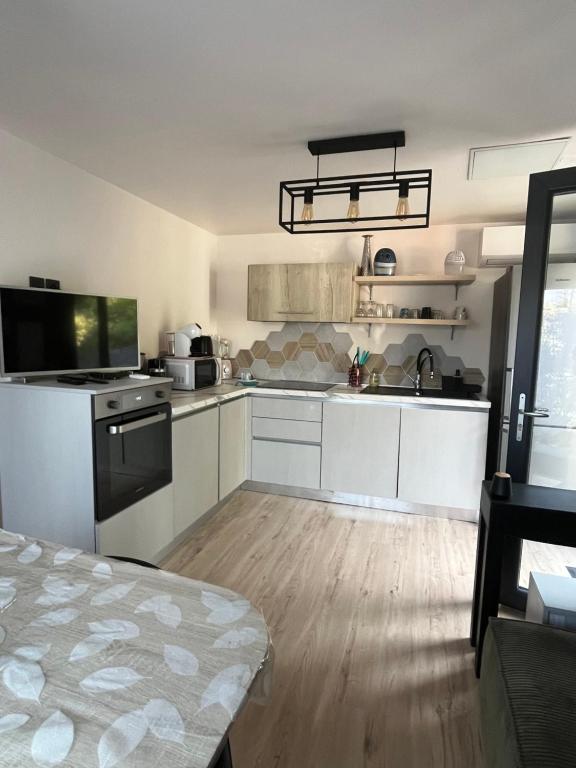 a kitchen with white cabinets and a wooden floor at Maison cosy au calme in La Colle-sur-Loup
