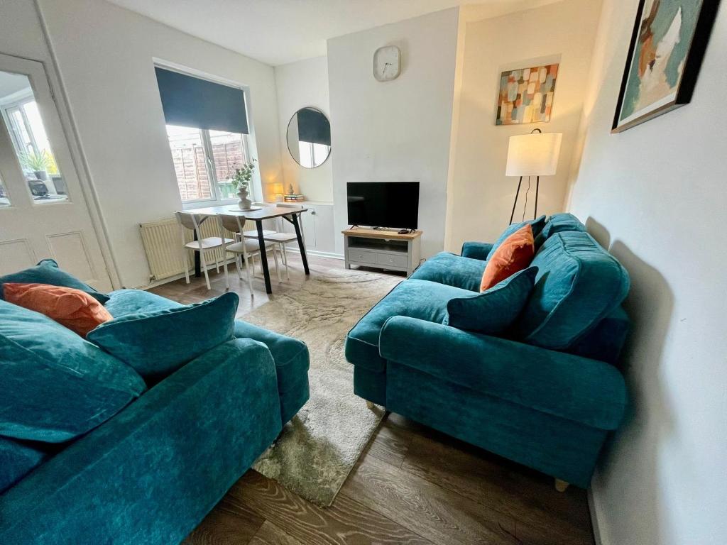 a living room with two blue couches and a table at Petal House, Gloucester - Large, Spacious and charming in Gloucestershire