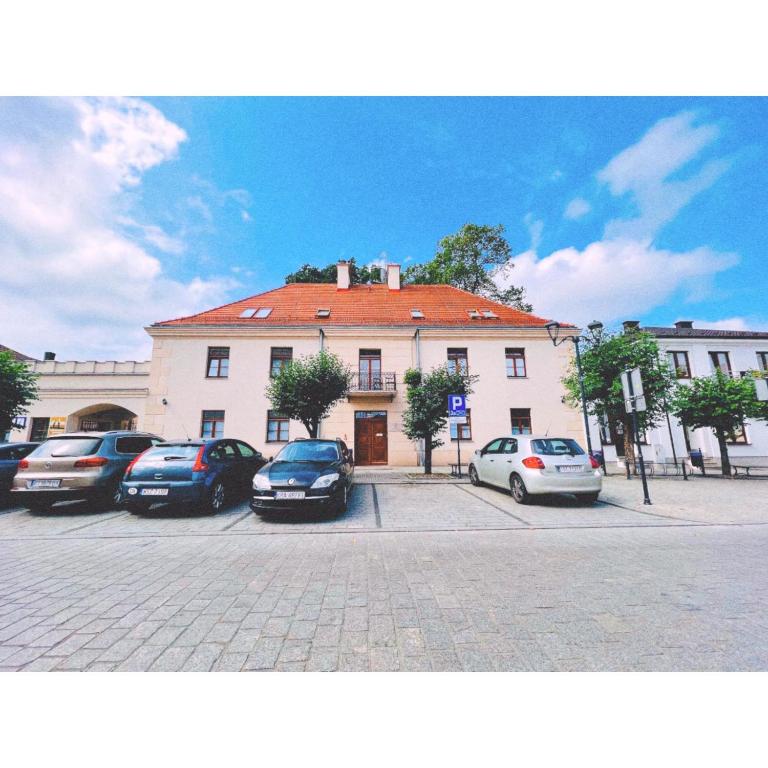 a building with cars parked in a parking lot at Hotel pod Dębem in Szydłowiec