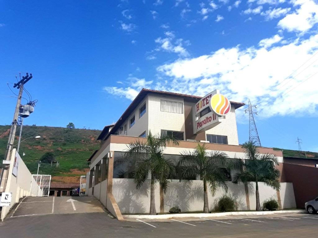 un restaurante de comida rápida con palmeras delante en Hotel Planalto 2, en Governador Valadares
