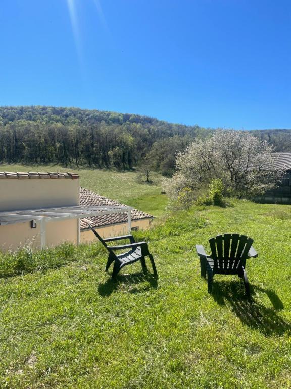 two benches sitting in the grass in a field at Le Chant des Arbres in Grane