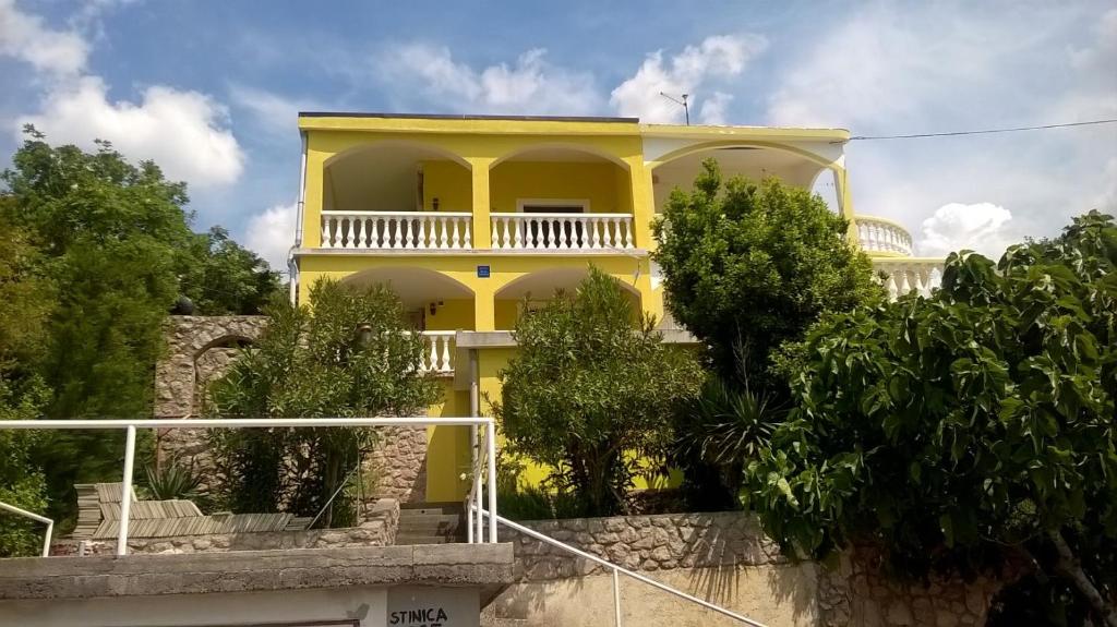 une maison jaune avec un balcon au-dessus dans l'établissement Apartment Stinica 26 E, à Jablanac