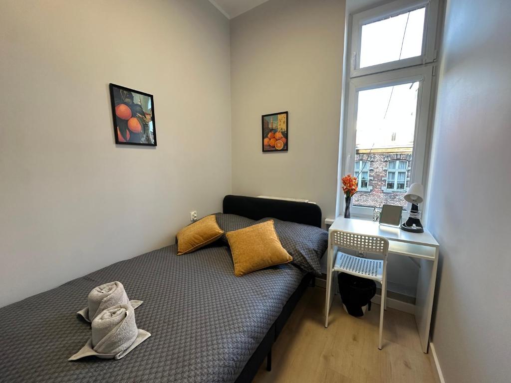 a bedroom with a bed and a desk and a window at MMRent Orange Room in Gdańsk