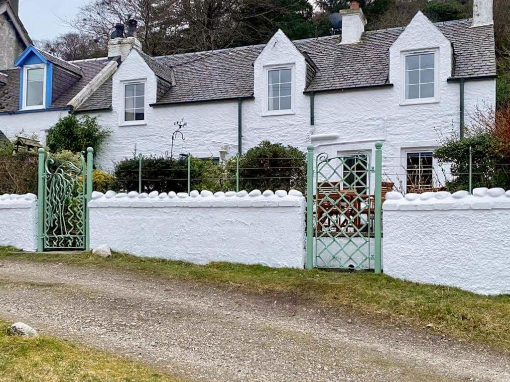a white fence in front of a white house at Croftbank in Lochranza