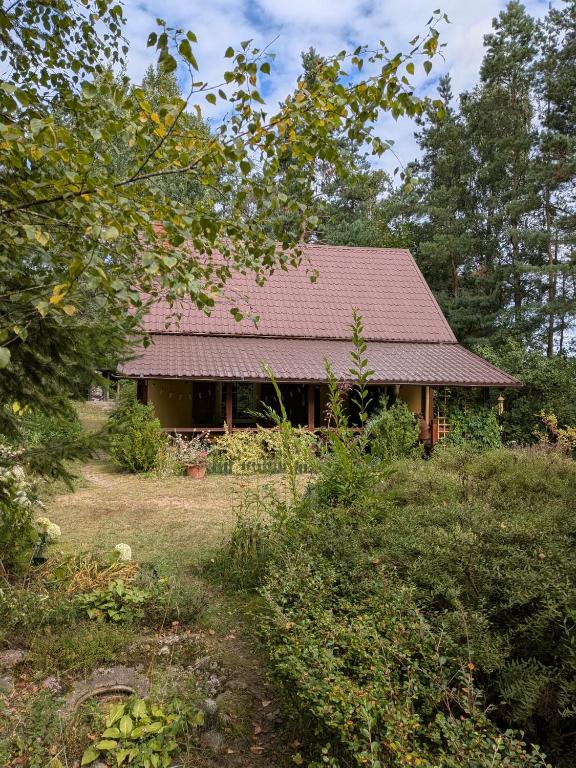 a house with a red roof in a yard at Gospodarstwo agroturystyczne nad jeziorem wśród lasów in Lipnica