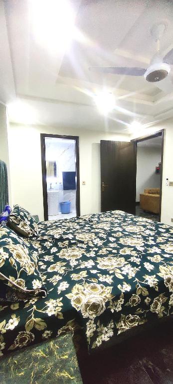 a bedroom with a large bed with a flowered blanket at Dawood Apartments Bahria Town Lahore in Lahore