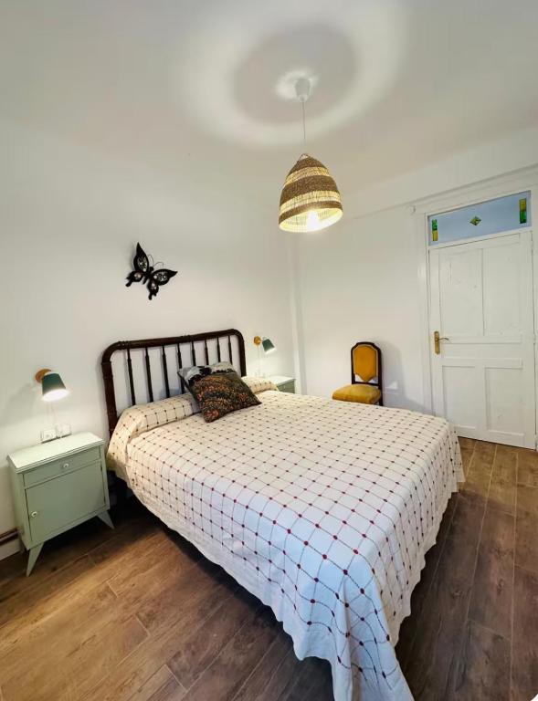 a bedroom with a bed with a checkered blanket and a lamp at Casa Claudio Palomar in Palomar de Arroyos