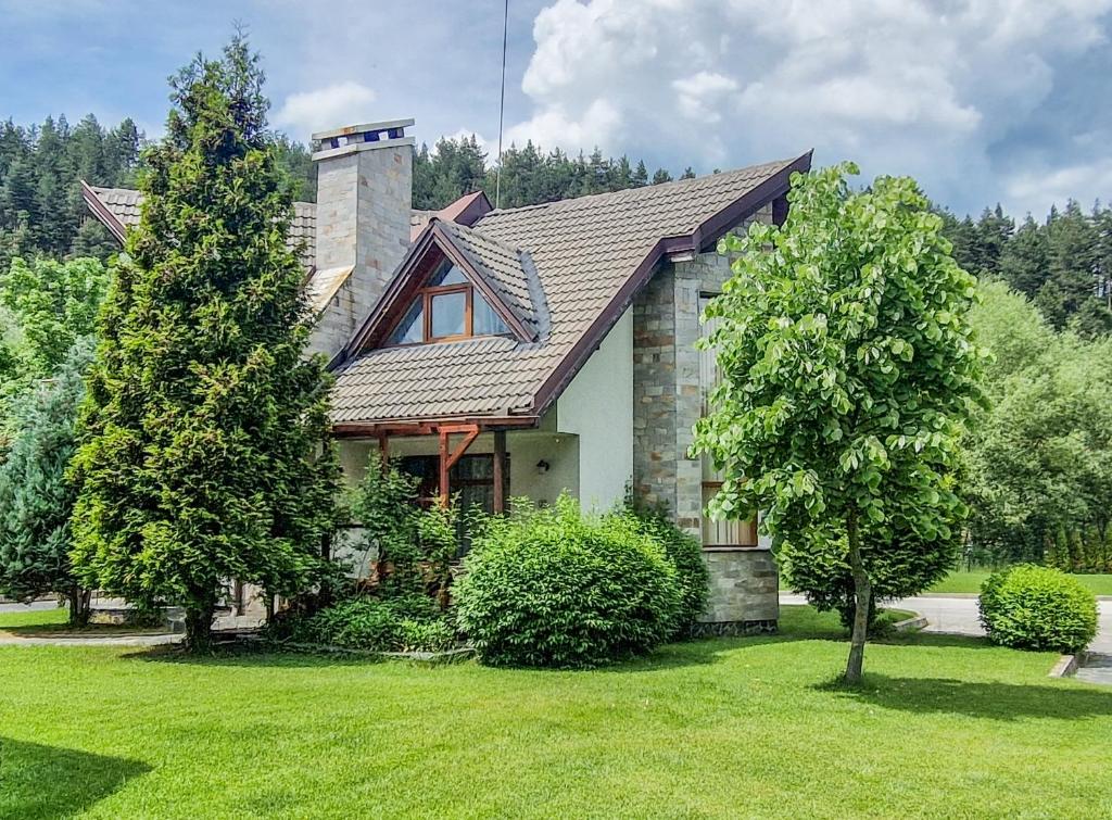 a house with a tree in the yard at Villa Deja Vu Private Jacuzzi & Sauna, Fireplace, 3 Bedrooms, near Bansko in Razlog