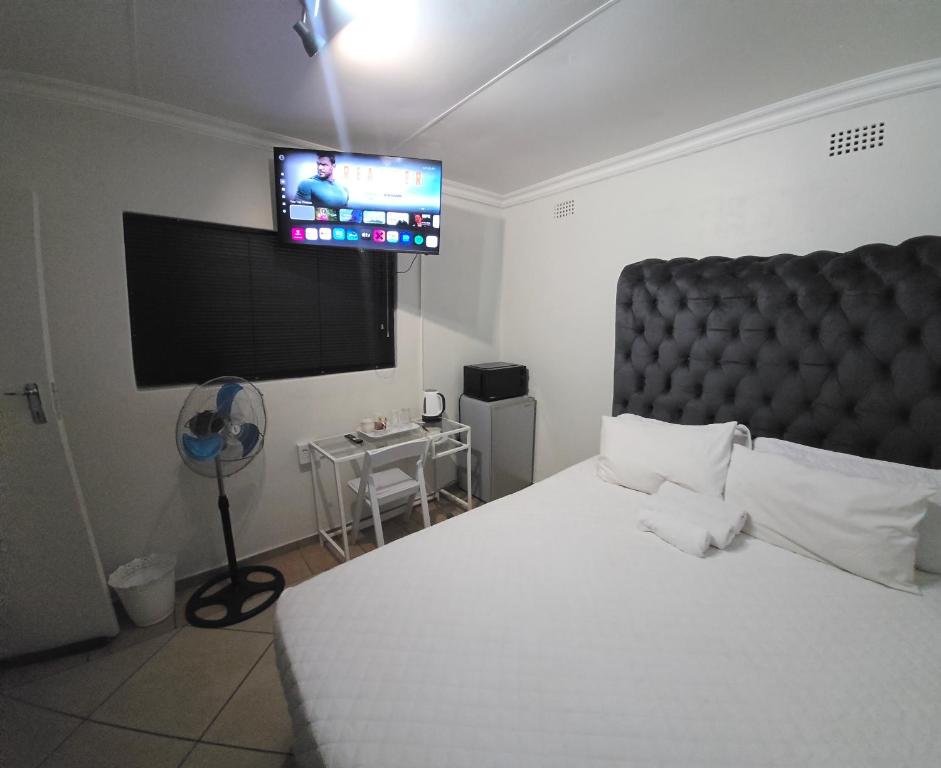 a bedroom with a large bed and a flat screen tv at Cjabaledi Guesthouse in Centurion