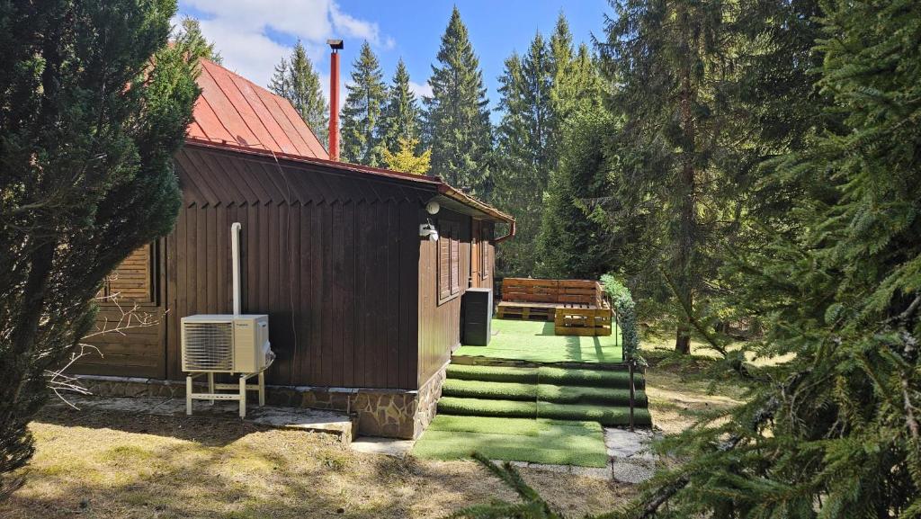 a small building with a green porch and a bench at Chata Bambi, Tatranská Štrba pri zubačke in Štrba