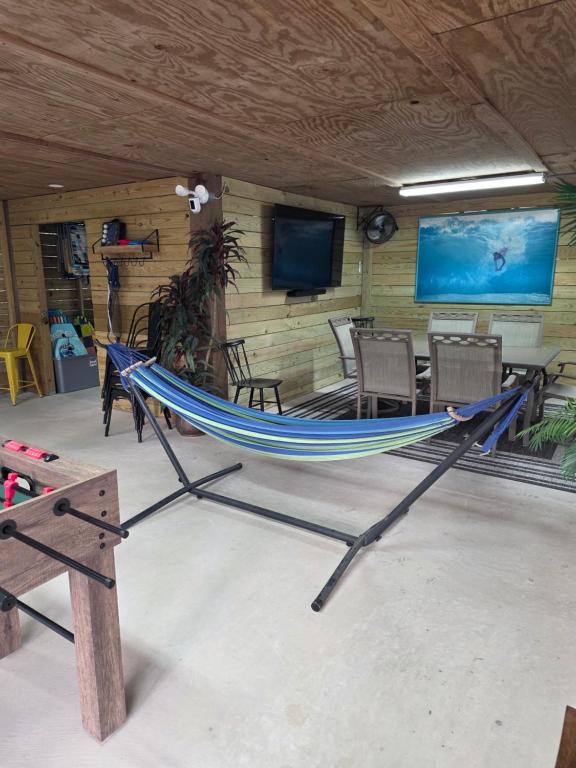 a hammock in a room with a table and a television at Pelican's Perch in Santa Rosa Beach