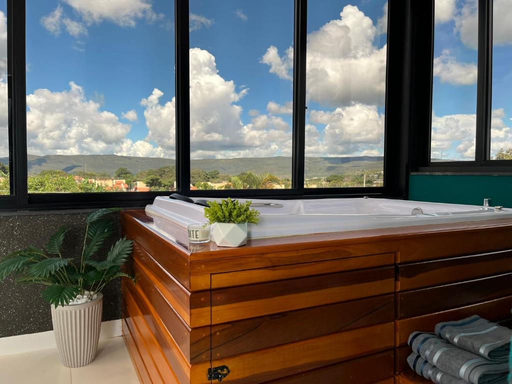 a bathroom with a bath tub in front of windows at Residencial Canto dos Passarinhos - Loft e Apartamentos in Alto Paraíso de Goiás