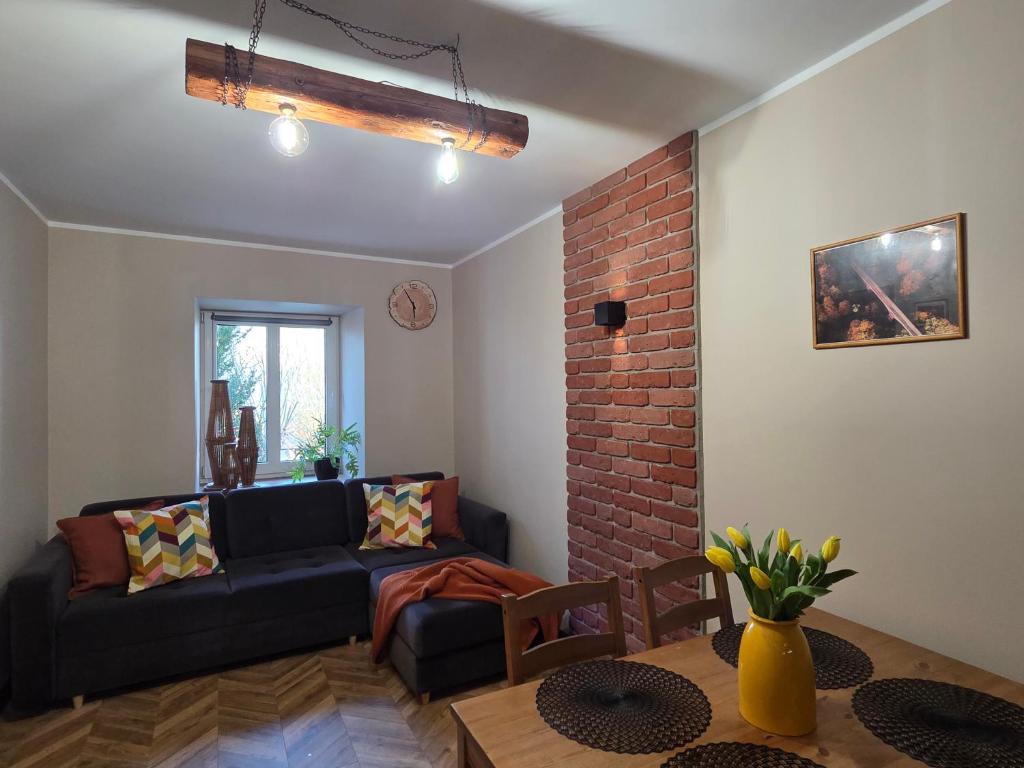 a living room with a couch and a brick wall at Apartament Wiaduktowy in Srebrna Góra
