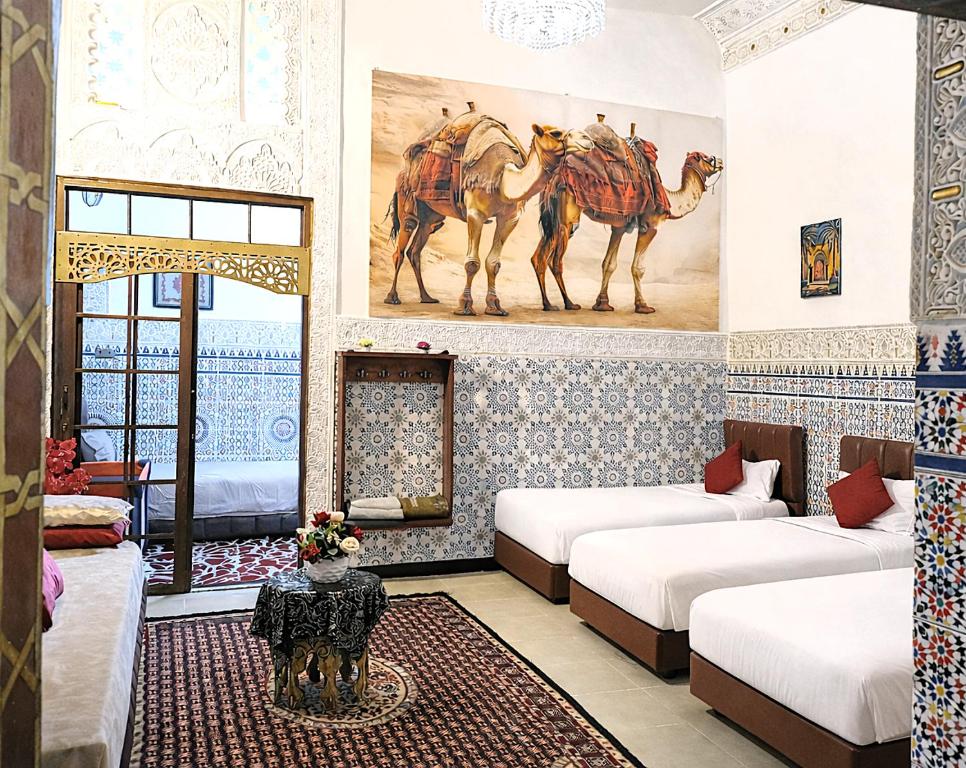 a room with two beds and paintings of camels on the wall at Riad Imperial Atlas in Meknès