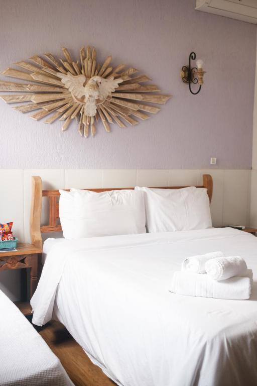 a bedroom with a white bed with a fan on the wall at Casa de Violeta Pousada in Tiradentes