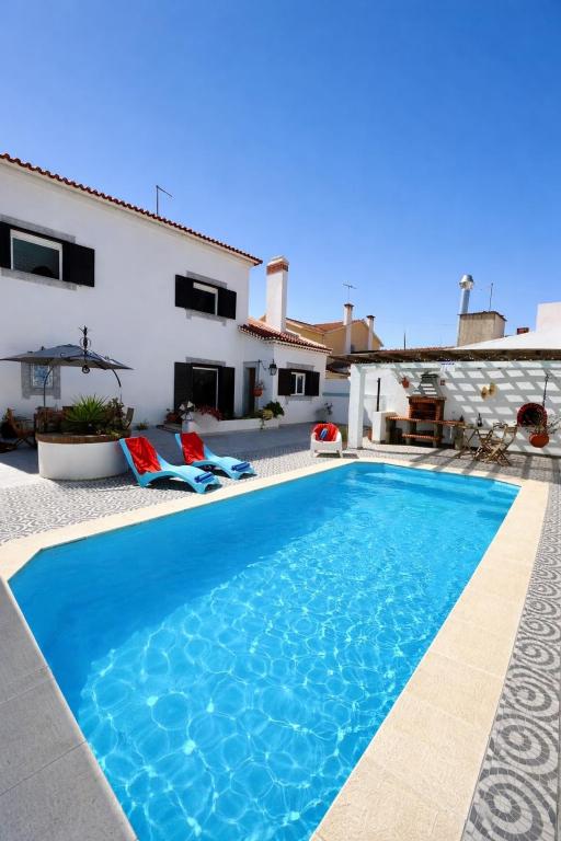 a villa with a swimming pool in front of a house at Morada da Vovó Alda in Almeirim