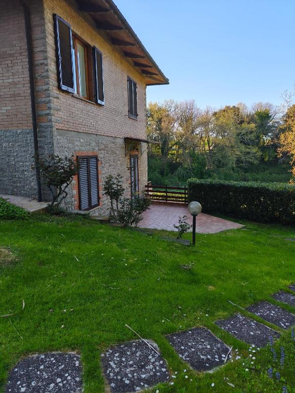 a house with a grass yard and a building at Il Boschetto in Le Grazie
