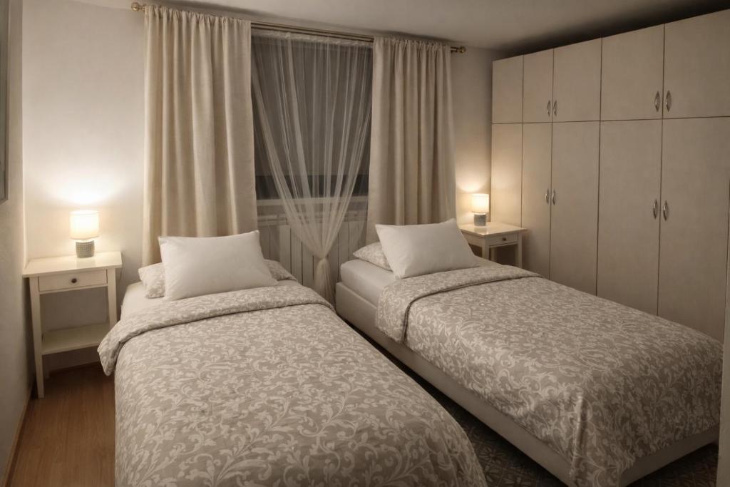 two beds in a bedroom with two lamps and a window at Dąbrowski in Nadarzyn