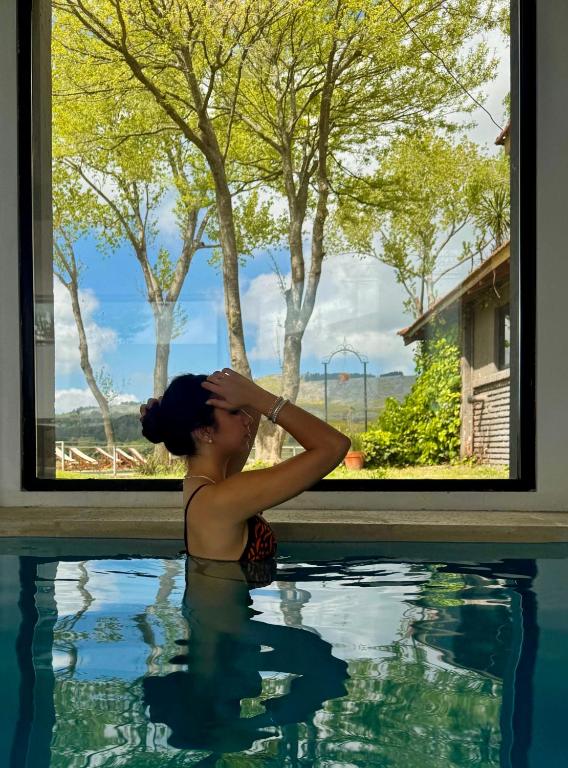 a woman sitting in a swimming pool looking out a window at Hotel El Paraiso De La Sierra in Tandil