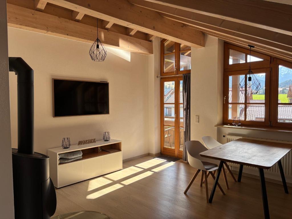a living room with a table and a flat screen tv at Chesa Piz mit privater Sauna in Pfronten