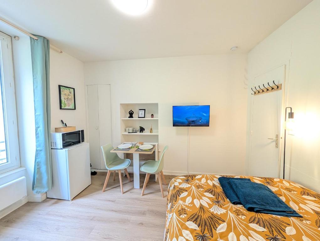 a bedroom with a bed and a table with chairs at Le Studio Évasion Tropicale in Quimper