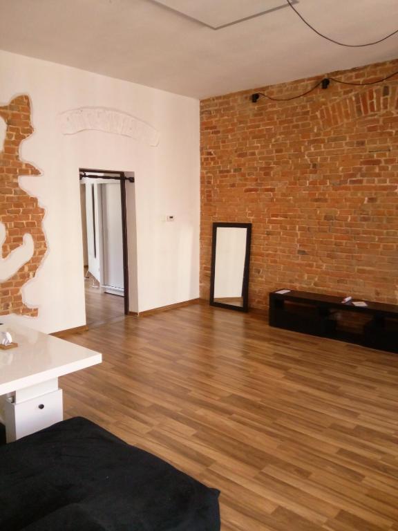 an empty room with a brick wall and wooden floors at TG Krakowska Kamienica in Tarnowskie Góry