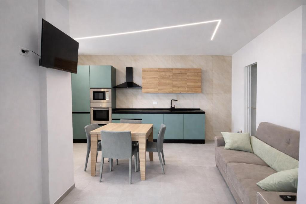 a kitchen and dining room with a table and a couch at Davs Home Appartamento per 4 a Lentini con WiFi Self Check in in Lentini