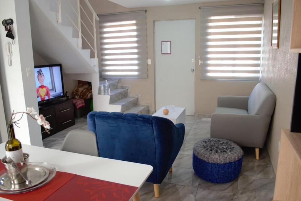 a living room with a blue chair and a staircase at Mi Casa Modernista cerca del AIFA in Santa Cruz Tecamac