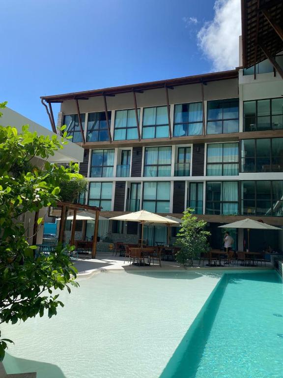 a large building with tables and umbrellas in front of it at Sunny Hall Porto de Galinhas PE - Flat Piscina Privativa in Porto De Galinhas