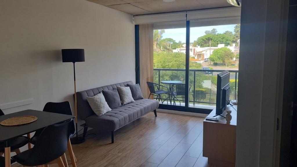 a living room with a couch and a table and a television at Seaside Piriápolis apartamento 105 in Piriápolis