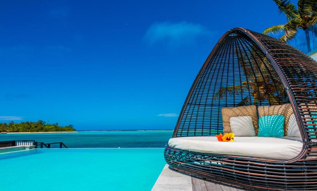 a hanging basket chair next to a swimming pool at Crystal Blue Lagoon Villas in Rarotonga