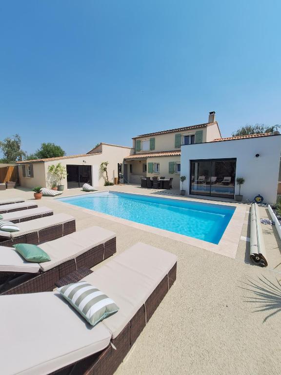 a swimming pool with chaise lounge chairs and a house at Villa du Rosais in Saint-Hilaire-de-Talmont