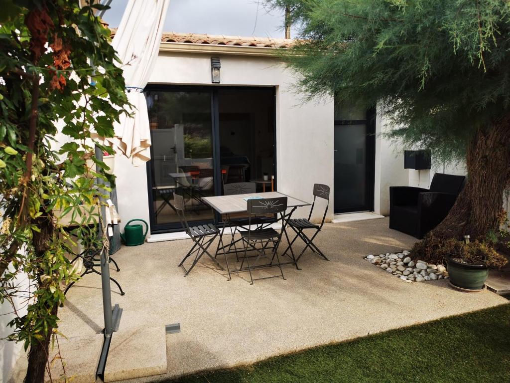 a patio with a table and chairs and a tree at "La Parenthèse balarucoise" in Balaruc-le-Vieux