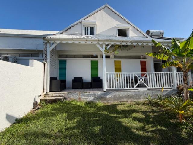 a white house with colorful doors and a porch at Chez Valé in Le Moule