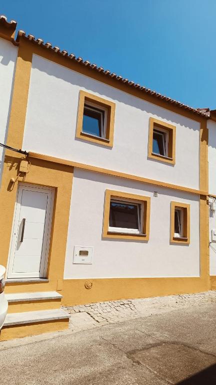 a yellow and white house with windows on a street at Lugar de São Braz in Alter do Chão