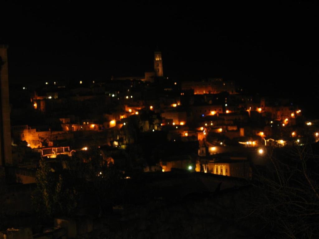 una città illuminata di notte con luci di La Seta Nei Sassi a Matera